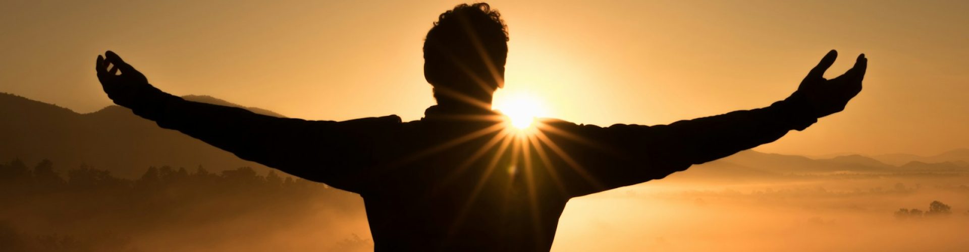 silhouette photo of man on cliff during sunset