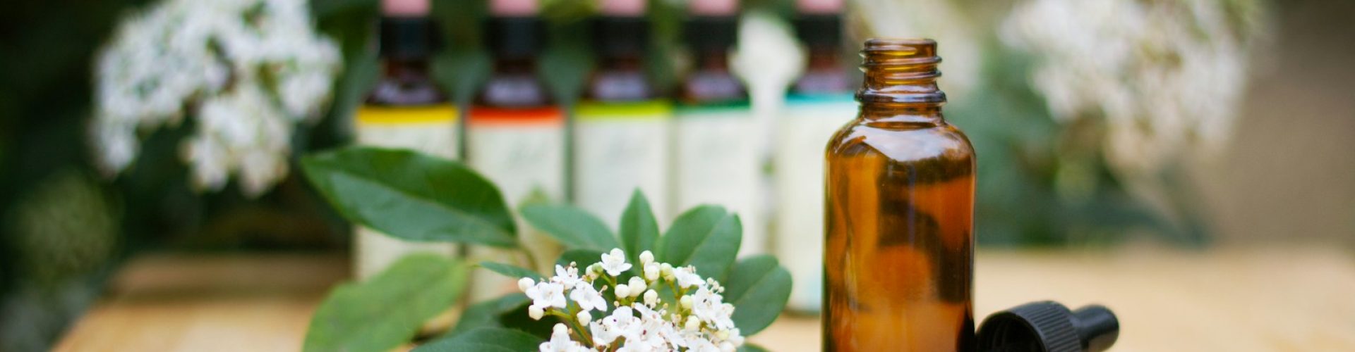 a bottle of essential oils sitting on a table next to a bunch of flowers
