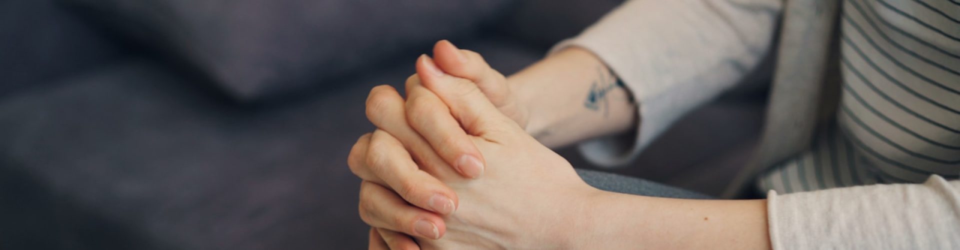 a woman sitting on a couch holding her hands together